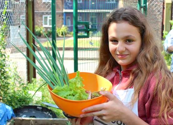 Girl holding up a bowl of vegetables