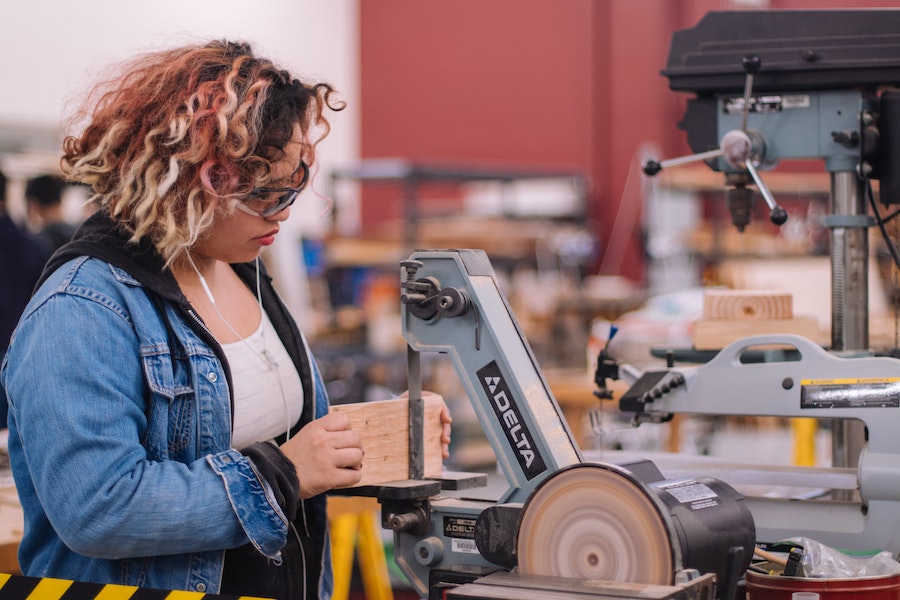 Young woman sanding wood with machinery