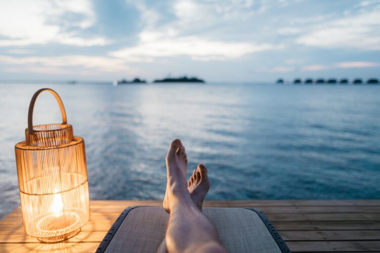 Shot of mans legs as he relaxes laying down with a view of the ocean ahead of him